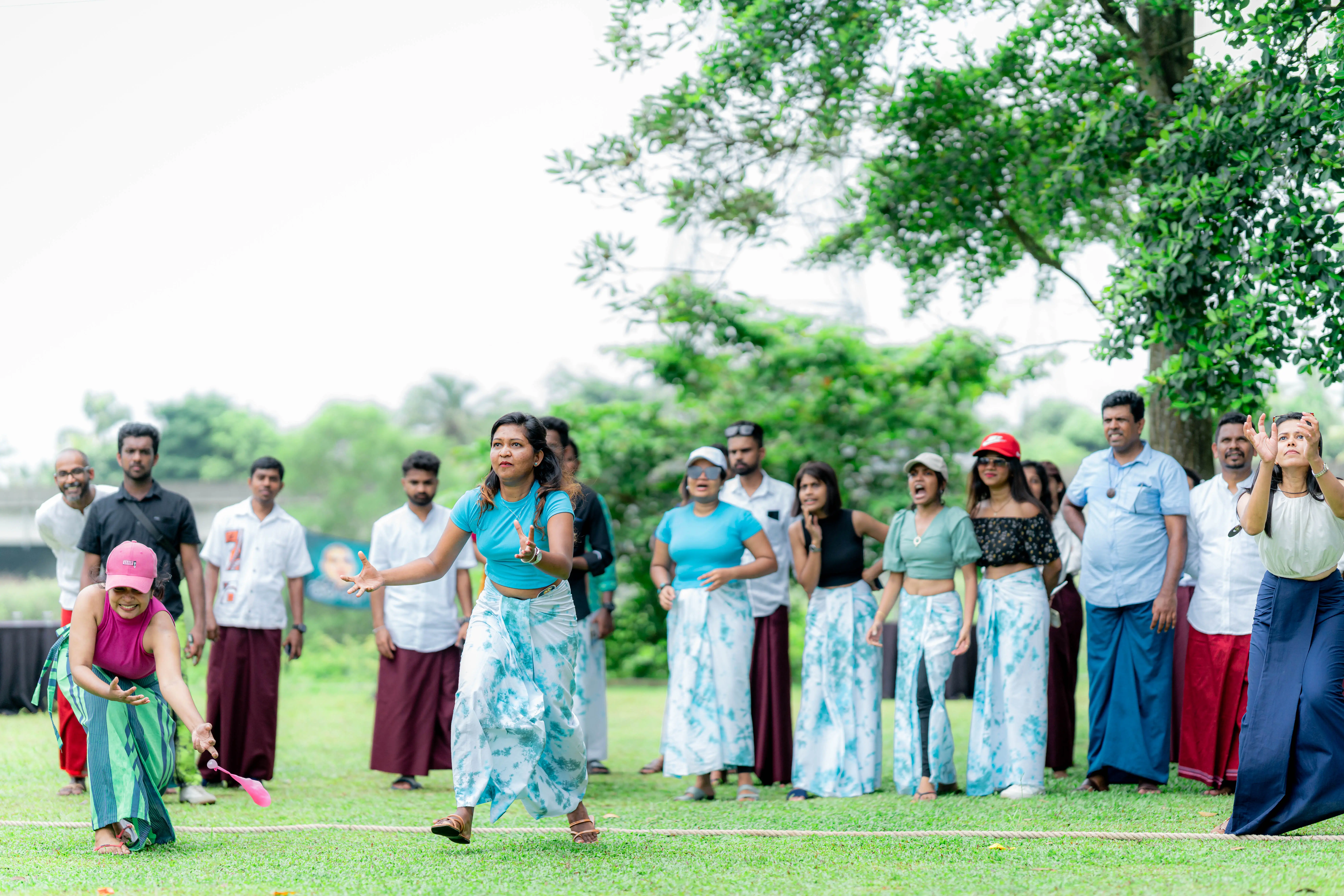 Three ladies employees trying to catch balloons and few colleagues supporting in behind