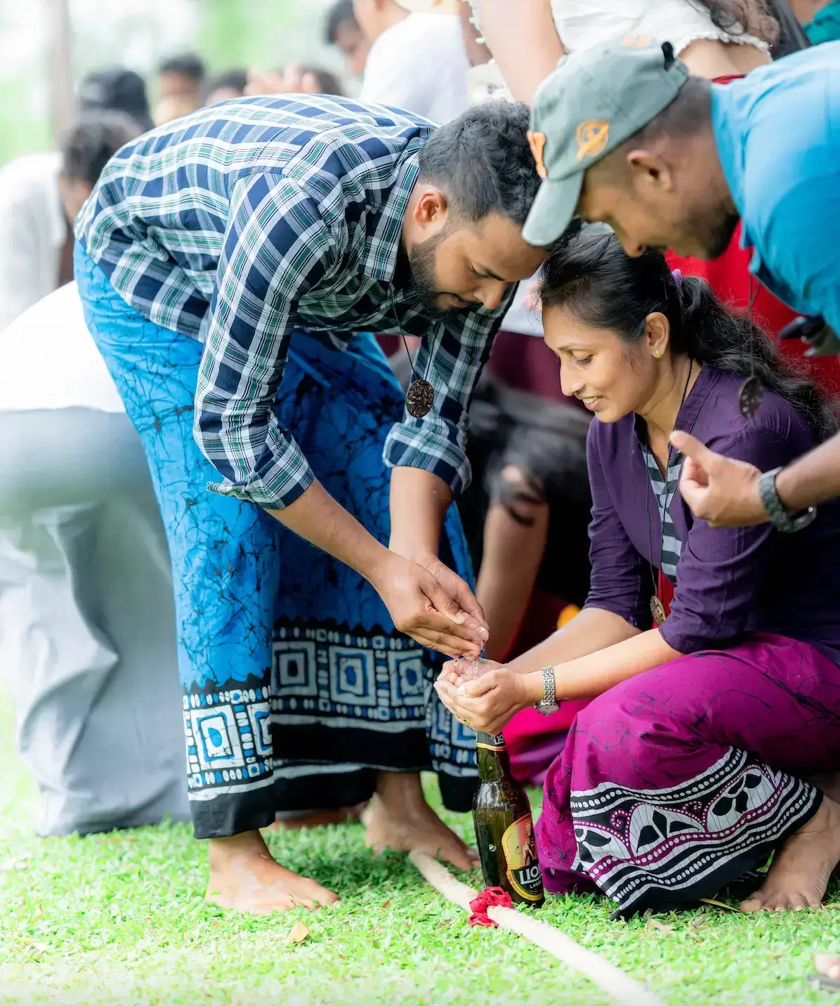 A male and female employee trying to fill a bottle with water from hands in a Aurudu game