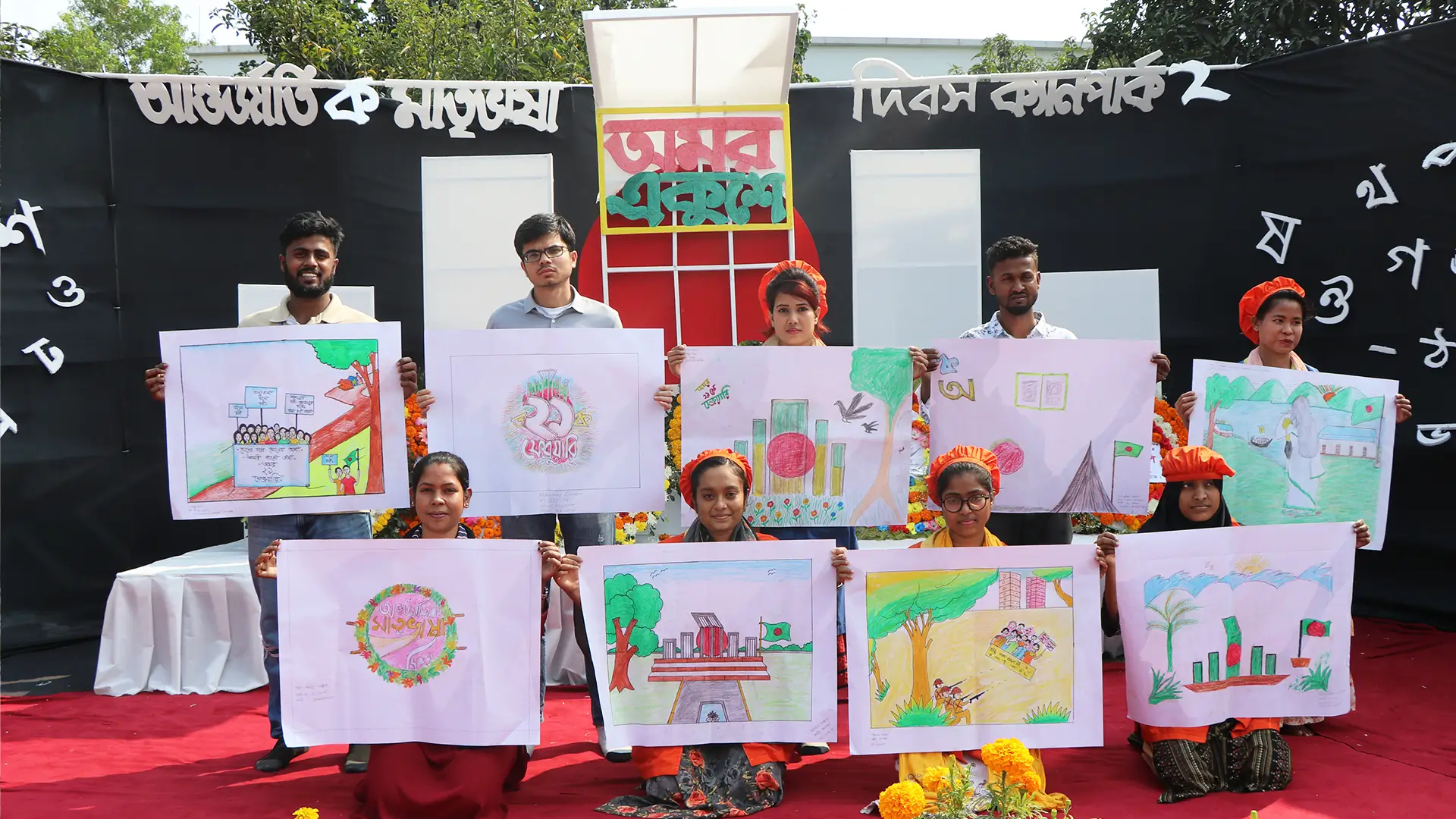 Hiradaramani employees holding the painting done for the language day in a stage