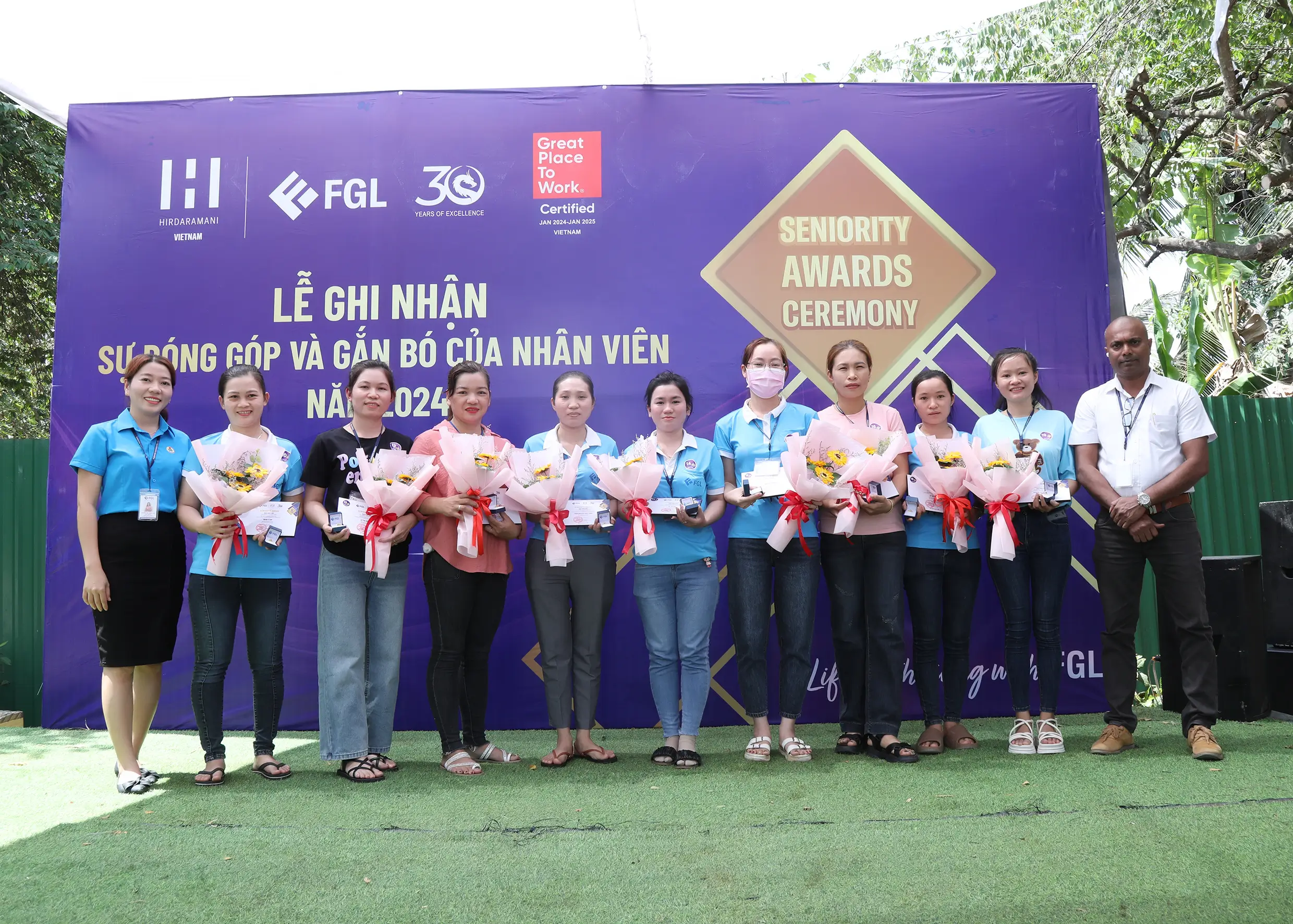 Employees who won the seniority awards in front of a event banner