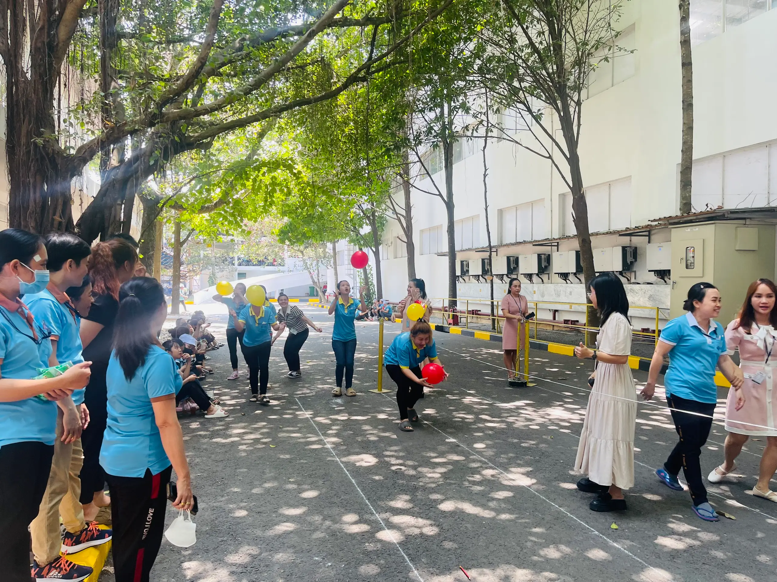 Female employees of Hirdaramani vietnam garment factory participating in a game played with balloons under a tree