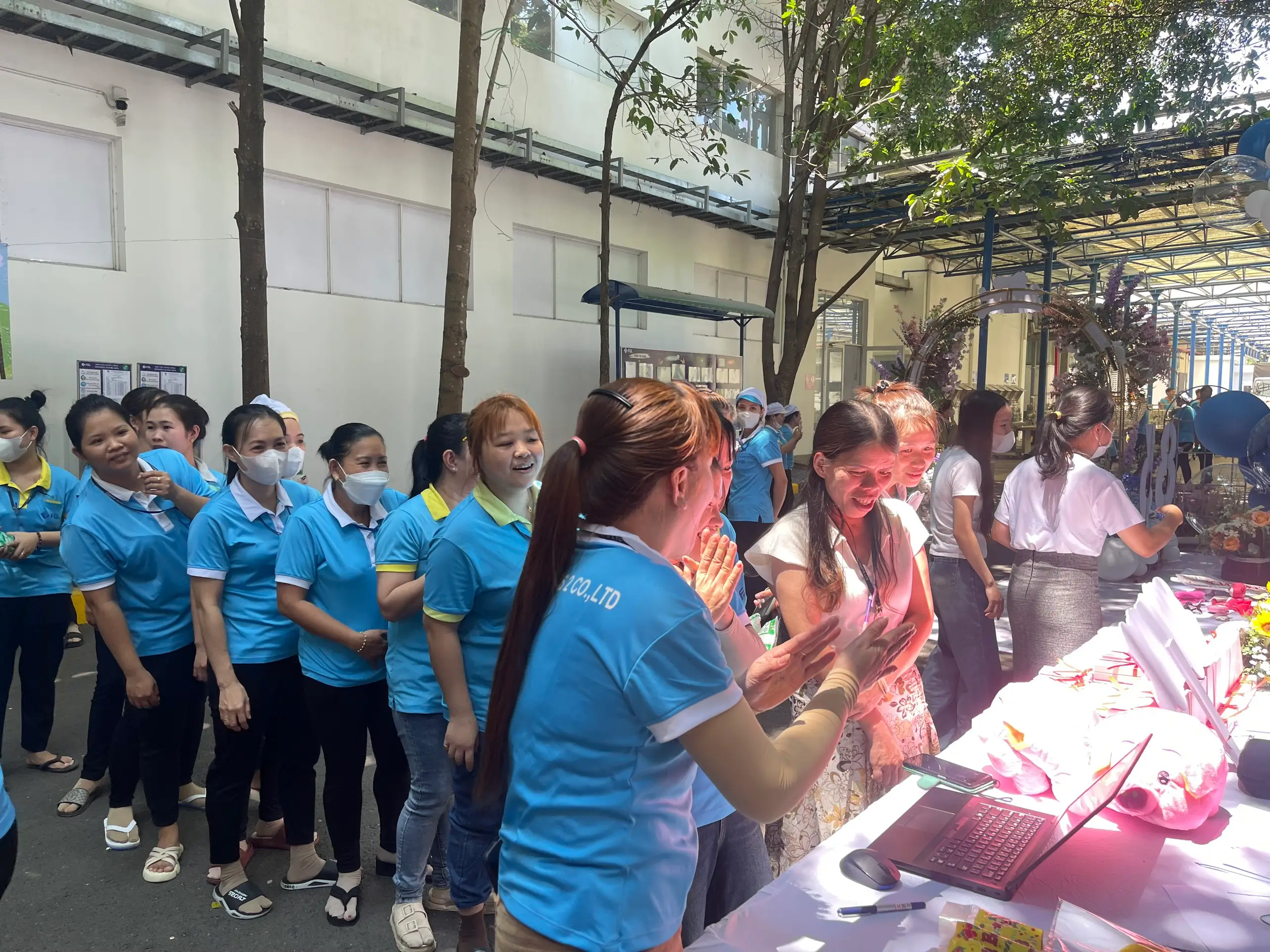 Few female employees in line in front of a table with a laptop